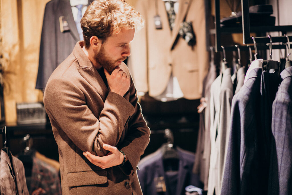 young handsome man choosing cloth at shop